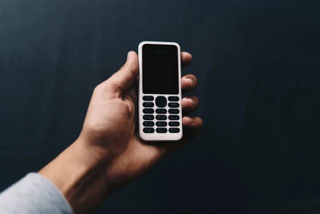 hand holding an old-style mobile phone with a number keypad, where 7726 spells SPAM