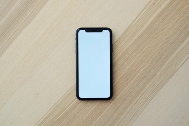 smartphone lying face up on a wooden table, ready to receive a scam call