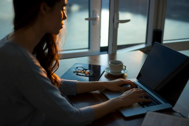 report fraud action fraud – woman reporting a scam online at her kitchen table in the evening