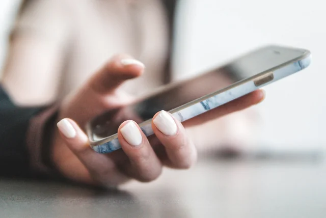 hand holding a smartphone used for free credit report apps like ClearScore and Credit Karma