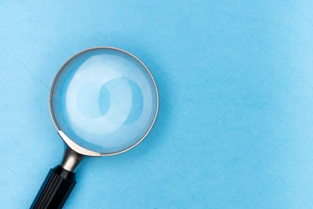 magnifying glass on a blue background, hunting for red flags on a credit report