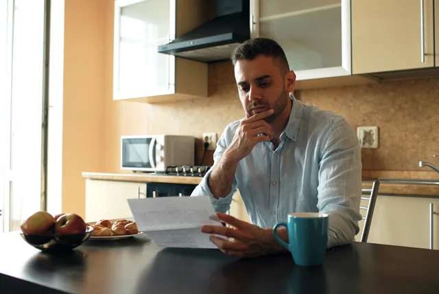 check credit report free uk - man reading a financial letter at his kitchen table