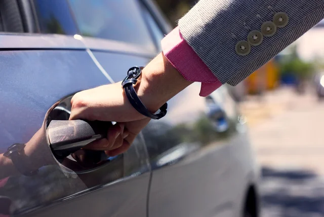 Hand opening a car door after sharing a licence check code at a hire desk