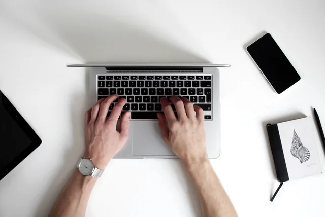 Hands typing on a laptop to report a suspected scam website to the NCSC
