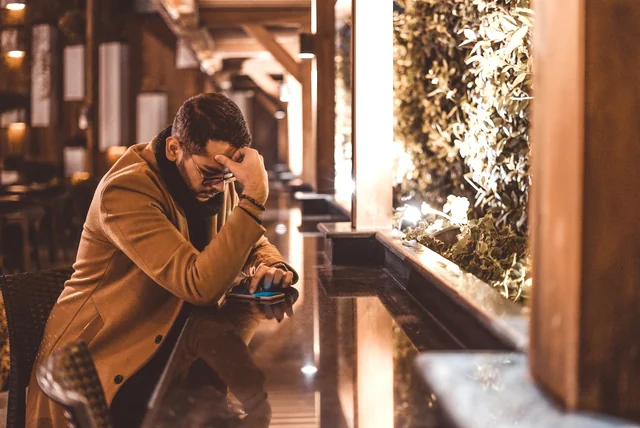 clicked on a scam link – man pausing over a message on his phone during a break