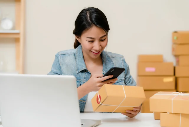 Shopper checking a parcel against her phone at home, wary of fake online shops