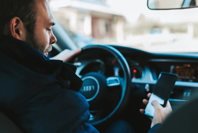 driver sitting in his car reading a suspicious parking fine text on his phone