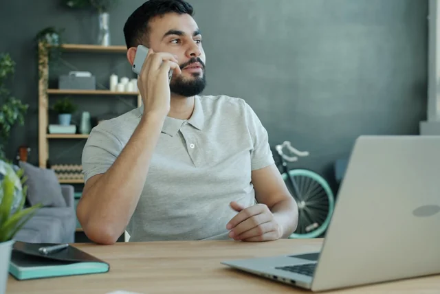 man calling his bank about identity fraud from his desk at home