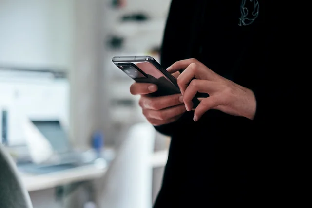 Person forwarding an HMRC scam text to 60599 and 7726 on a smartphone