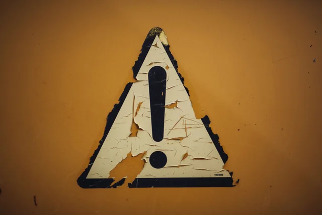 Worn warning triangle symbolising the red flags of a fake HMRC text message