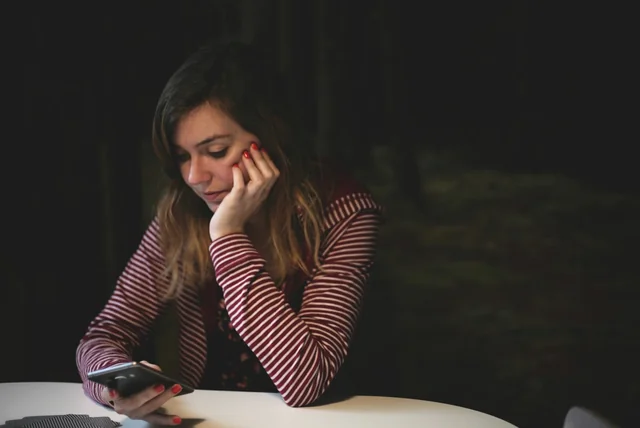 Woman studying her phone, unsure which health app uses her NHS login
