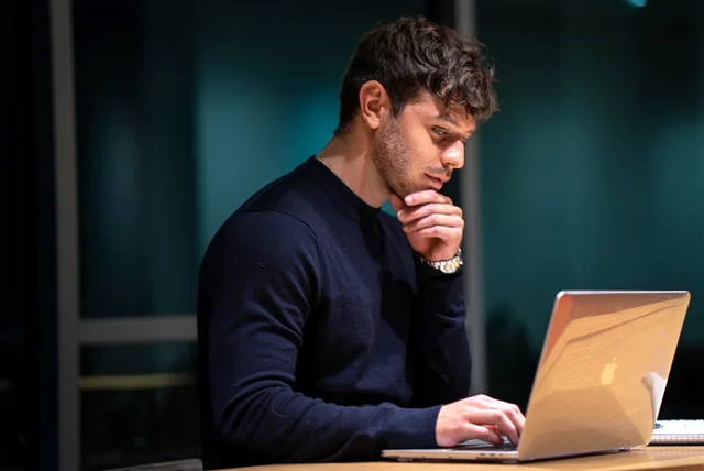 worried man at a laptop changing passwords after clicking a scam email link