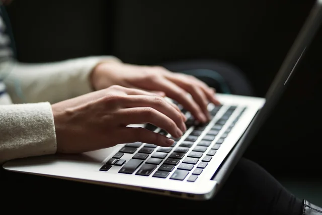 hands on a laptop using the report phishing button in a webmail inbox
