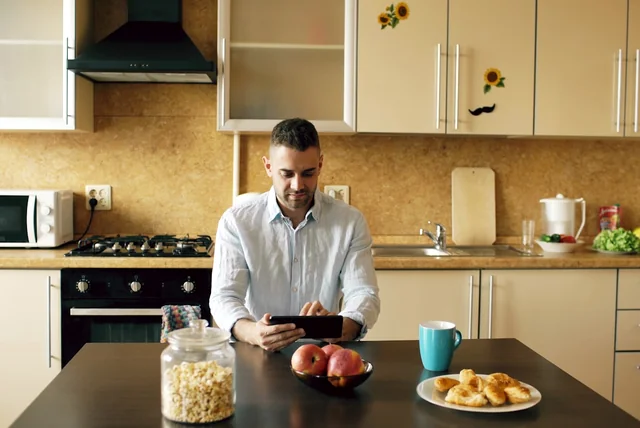 report scam email uk – man reading a suspicious email on a tablet at breakfast