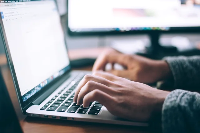 hands typing a suspicious web address into the NCSC report form on a laptop