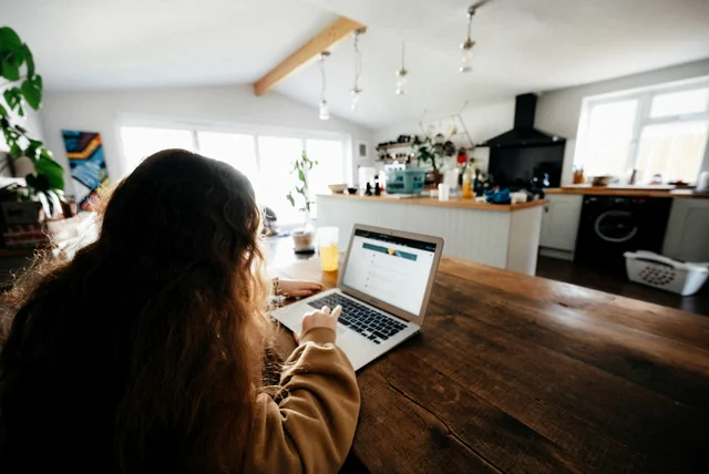 report scam website – woman reporting a suspicious website on her laptop at the kitchen table