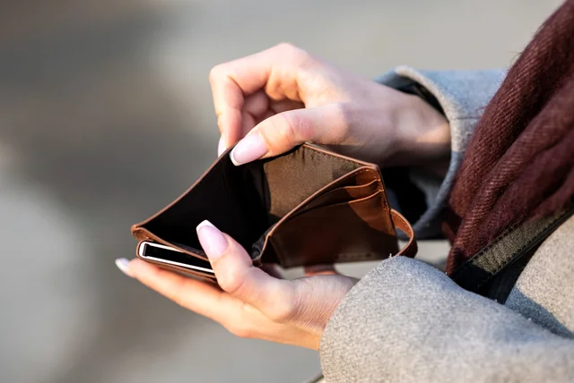 Hands holding a leather wallet and a phone representing the GOV.UK Wallet