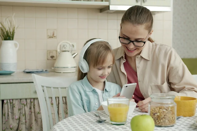 a parent with their child and a phone at the kitchen table, the bond hi mum scammers exploit